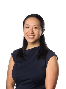 A woman wearing a black shirt smile in front of a white background.